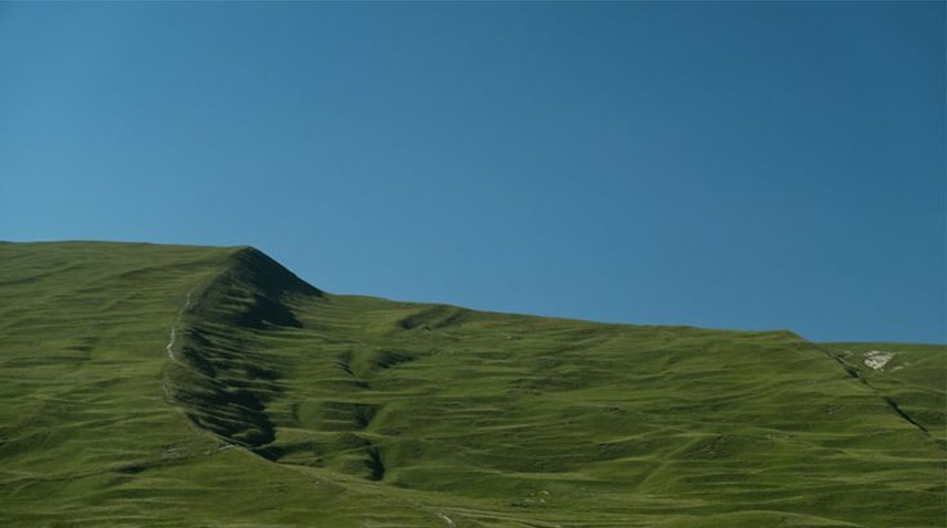 Green mountain ridges beneath a blue sky